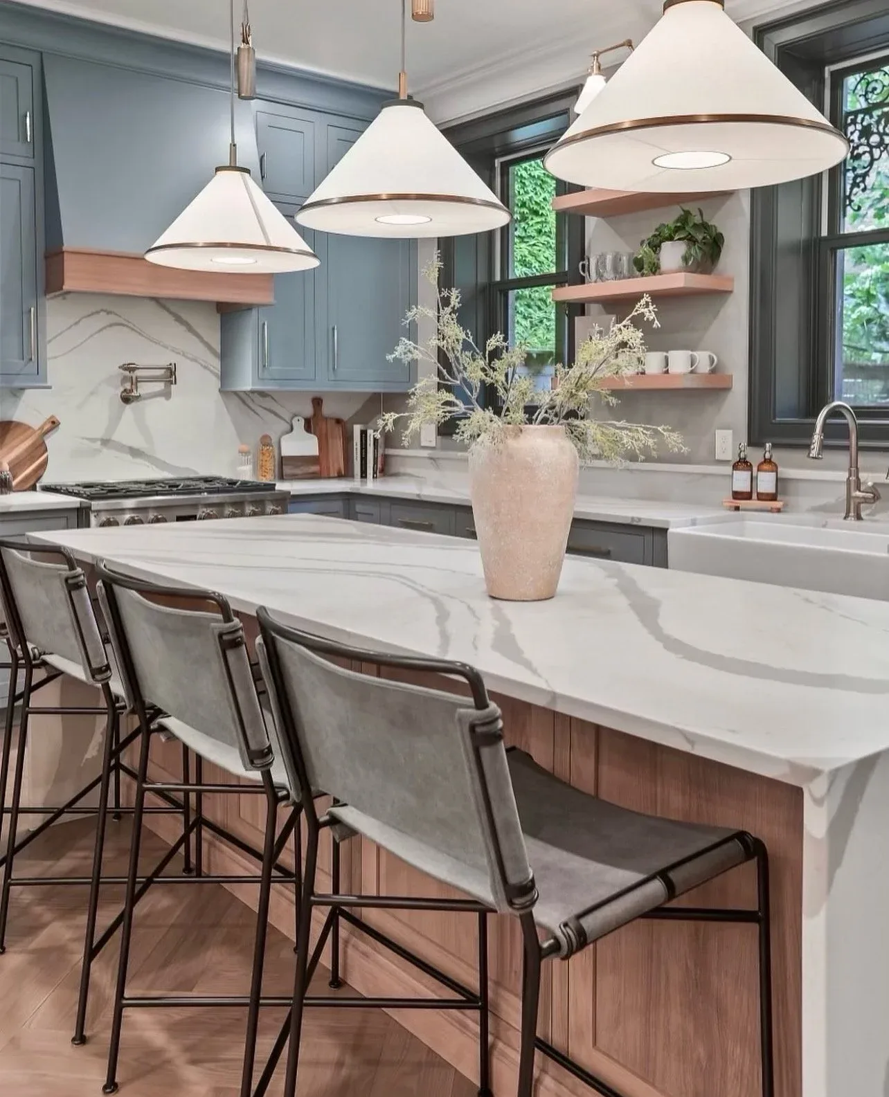 Fully custom blue kitchen with marble island and brass pendant lighting